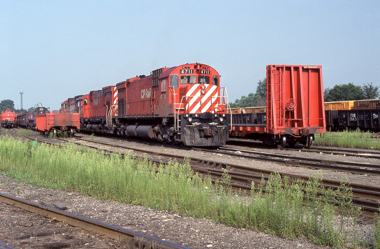 Canadian Pacific M636 4711 is shown along with 4723 and an unidentifiable sister resting at the former T, H & B Aberdeen Yard in Hamilton. In an attempt to prolong the lifespan of the veteran six-axle MLW fleet, in 1988 CP had M636 4711 rebuilt with a like horsepower Caterpillar 3608 Marine Service prime mover at Peaker Services in Brighton, Michigan. Apparently the new prime mover required considerably more breathing capacity as evidenced by the enlarged and expanded carbody filter arrangement (compared to 4723). Note also the relocated horns and lack of multi-mark emblem at the rear of the hood. While successful, the overall expenditure was considered to be cost prohibitive and no further units were so modified. Nevertheless, the transplant did by her an additional three years of service with CP compared to the rest of big MLW’s which had been displaced by the incoming horde of GE AC4400CW’s. Sold to Minnesota Commercial Railroad in July 1998 and renumbered, the venerable unit continues to soldier on with her replacement power plant. Following a period of storage 71 returned to service in mid-2011. The Caterpillar sound is quite distinct from the original Alco 251 ‘chug, chug, chug’. For a sample of her music go to http://www.youtube.com/watch?v=lBYUcRqIsHE