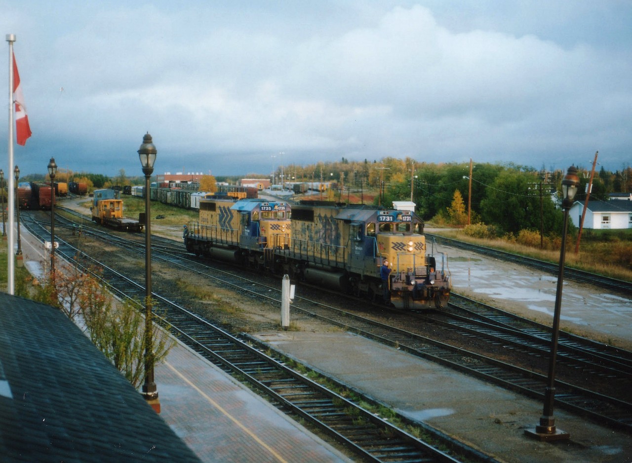 Problem: How to get a decent view of Cochrane's ONR yard. Solution:  Rent a room at the Station Hotel and crawl out onto the roof. Not what I hoped it would be, but I liked it. The management had a somewhat dimmer view. This was the only image in which I at least got a bit of bright sky after a good rain. One can see the shop building in the distance, as well as a number of Polar Bear Express coaches....in the foreground ONR 1731 and 1735 had just parked their train on the far left in photo. The Hotel is a nice place to stay, and I recommend it; I just hope there are no "Trespassing On Roof Prohibited" signs anywhere on the property now........