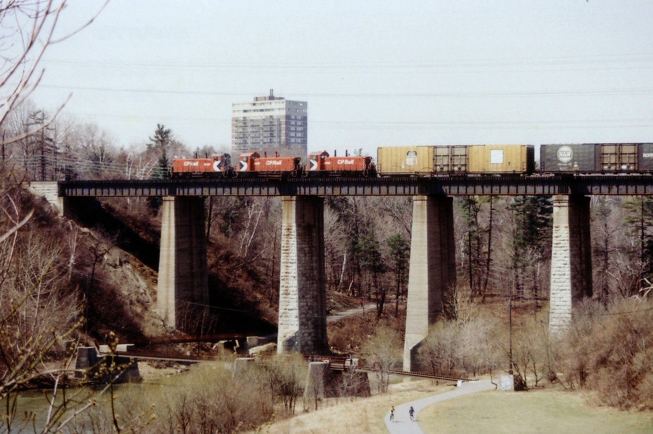 The massive cube cars, loaded with auto parts for Ford appear to overpower the diminutive switchers that are in charge of them. CP SW1200RS 8127, 8107 and 8156 are crossing the Humber River westbound at roughly mile 7.3 Galt sub. All but one of the 72 locos in this series were off the roster according to the CTG by 2013; having been built in the late 1950s; ending up victims of old age. Below, one can see it is a nice spring day and the citizens are taking advantage of spring awakening.