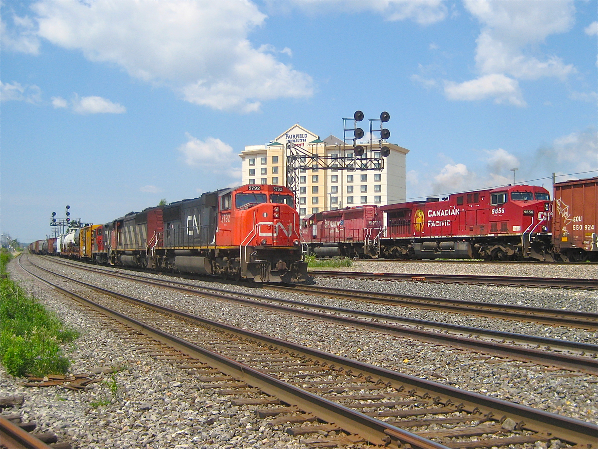 At left is a CN westbound with CN 5792, CN 5543 & CN 7065. At right is a CP westbound with CP 5773 & CP 9656. A lot has changed since. The CN-CP interchange track which is in between the two trains has been removed and the CP signal bridge has been replaced. This vantage point (a favourite of mine) is also no longer accessible due to ongoing construction. For more train photos, check out http://www.flickr.com/photos/mtlwestrailfan/