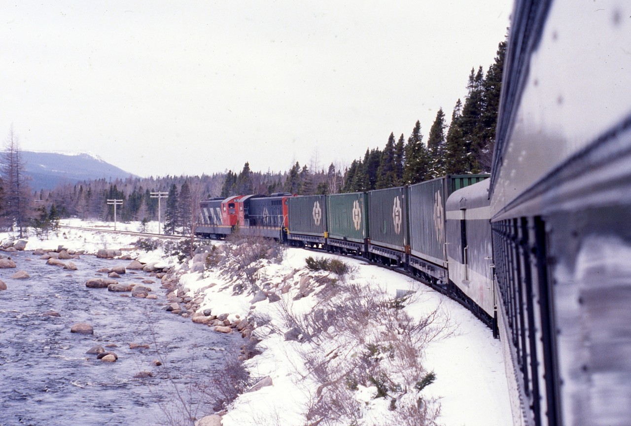 KITTYS BROOK 1988
Terra Transport Mixed Extra 935 West, formerly train #203, follows Kitty's 
Brook in Newfoundland to the flag stop bearing the same name on April 16, 1988. This was my 
third of five trips by train trip over the line during the last two years of 
operation and the first on the recently refurbished coach. Departing Bishops 
Falls with only passenger equipment, the two NF210s picked up the four 
containers at Grand Falls, thus making it a true mixed. This photo and it's 
contemporary update along with many others can be seen in 'RAILS ACROSS THE 
ROCK - A Then & Now Celebration of the Newfoundland Railway' by Kenneth G. 
Pieroway and published by Creative Book Publishing of St. John's, NL. – 
Author photo.