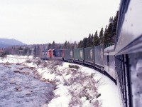 KITTYS BROOK 1988
Terra Transport Mixed Extra 935 West, formerly train #203, follows Kitty's 
Brook in Newfoundland to the flag stop bearing the same name on April 16, 1988. This was my 
third of five trips by train trip over the line during the last two years of 
operation and the first on the recently refurbished coach. Departing Bishops 
Falls with only passenger equipment, the two NF210s picked up the four 
containers at Grand Falls, thus making it a true mixed. This photo and it's 
contemporary update along with many others can be seen in 'RAILS ACROSS THE 
ROCK - A Then & Now Celebration of the Newfoundland Railway' by Kenneth G. 
Pieroway and published by Creative Book Publishing of St. John's, NL. – 
Author photo.

