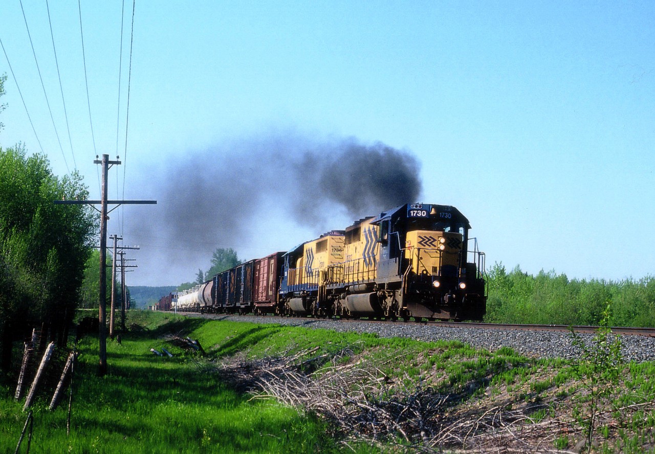 My best experiences with getting a decent sun angle on the ONR as the trains leave Englehart is around the curve just north of town. However, it felt to me this morning that the engineer was wise to my plan. He really turned on the jets as the train made the curve and I was hard pressed, tearing along rugged gravel roads, to get ahead of him. There was about 10 seconds to spare to shoot this as the train came up to Mile 4. Fortunately, we are looking somewhat in a westward direction, and the slight breeze carried my clouds of dust off the other way.  ONR 1730 and 1736 on otherwise a crystal clear morning.