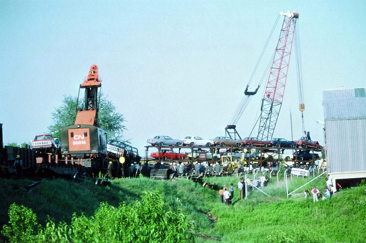 I can still recall it was when my 1971 Cougar was on its last legs (due to overuse) and I was wondering how I was going to scrape up for the next 'railfanning vehicle' when I came across this wreck in Simcoe. Here, all kinds of cars, many wrecked, being tossed around by the CN Hooks like they were scrap metal. It was sickening to watch, so, of course, I watched. N&W train #90 east, with NW 3659 and 3726 on the point,apparently had a gearcase cover fall off, it caught on a switch and derailed the power, one of which plunged off the Hwy 24 overpass and caught fire. The train piled up. In the consist were all kinds of new cars, many makes, mostly Fords, and it was a sad sight; save for the autoracks of Pintos, clunkers that I wouldn't get caught dead in anyway. :o) In this image, taken day after the incident, it looks to be a Maverick that is being hoisted by the crane on the right. Quite the crowd showed up to watch the cleanup, and in this photo there are quite the number of railroad workers (and a few Tall Foreheads) as well. I believe both locomotives were scrapped.
