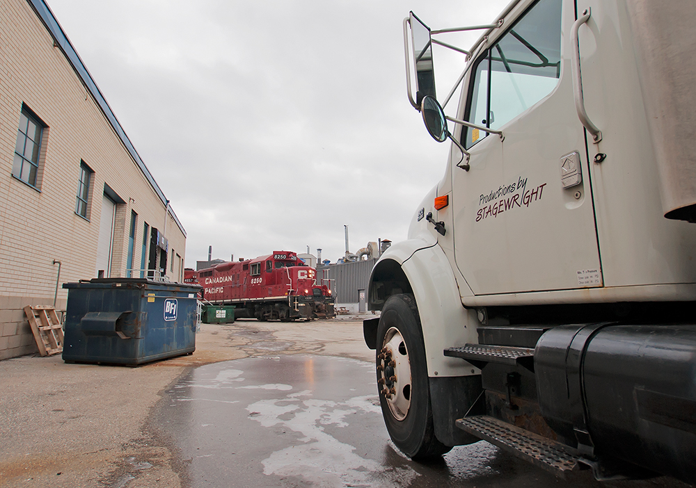 Appearing out from behind the building, CP 8250 leads a GP40 after switching Polytainers.
