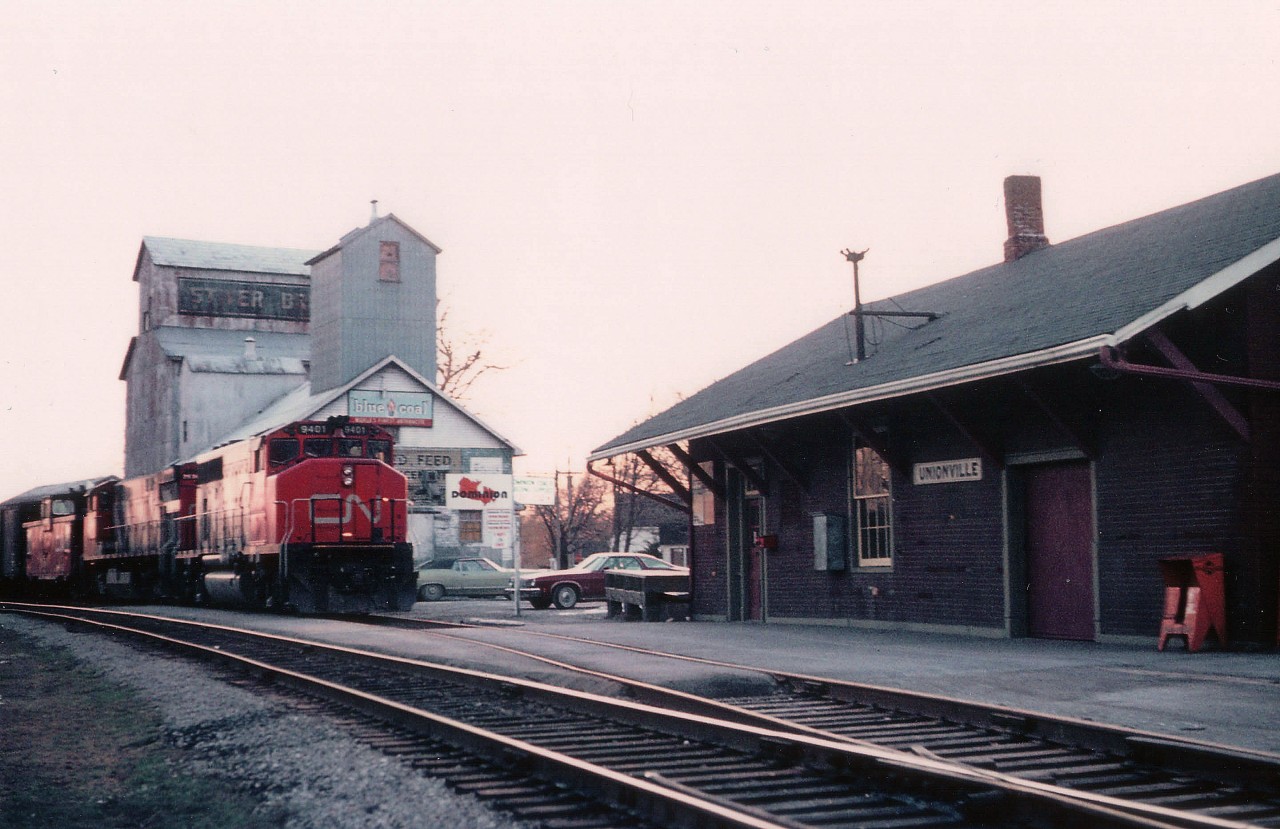 One of my more difficult experiences for some reason was catching a freight train northbound thru Unionville. And this one just barely made town by sunset. CN 9401 leads this local run......grain building and station provide a quaint setting; note open self-serve 25¢ "Globe" paper box. The station was served daily by Buddcars for people commuting to Toronto. As with many old time stations in the GTA, the building has been preserved as a GO Transit stop. (Uxbridge sub ran from Scarborough to Lindsay back in 1976)
