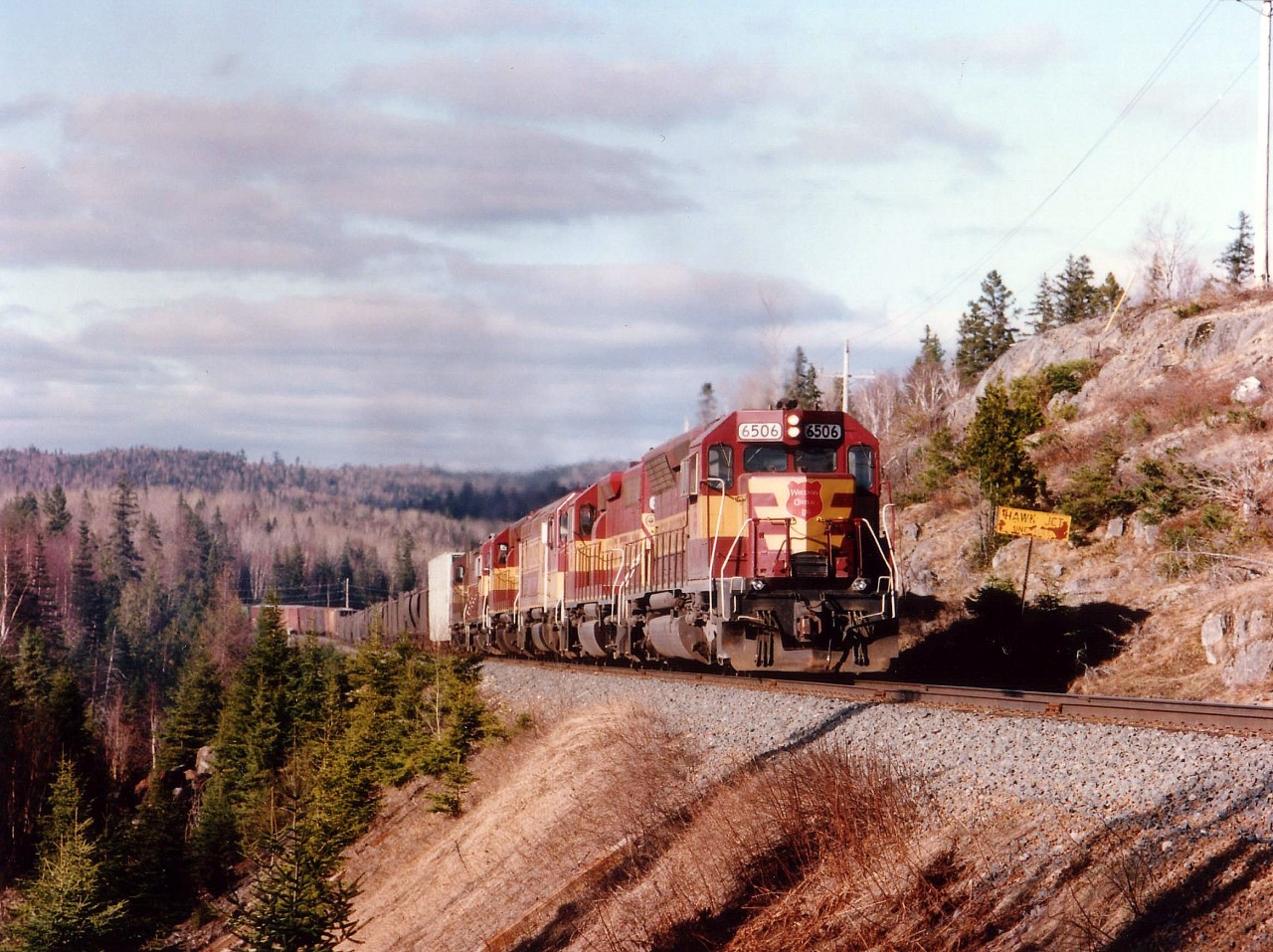 After all these years of seeing the Algoma Central in this part of the province, absorbing the sight of the "foreign" Wisconsin Central power was difficult. But still, a welcome change. Here we see daily southbound #10, mixed freight, climbing the stiff grade out of town by the Hawk Jct. approach marker; WC 6506, 3012, 6655, 6604, 2252 and 2052.  The ACR was taken over by WC on January 31, 1995, The WC, in turn, was bought out by CN in October 2001. So, the period of solid WC power was shortlived, and now long past.