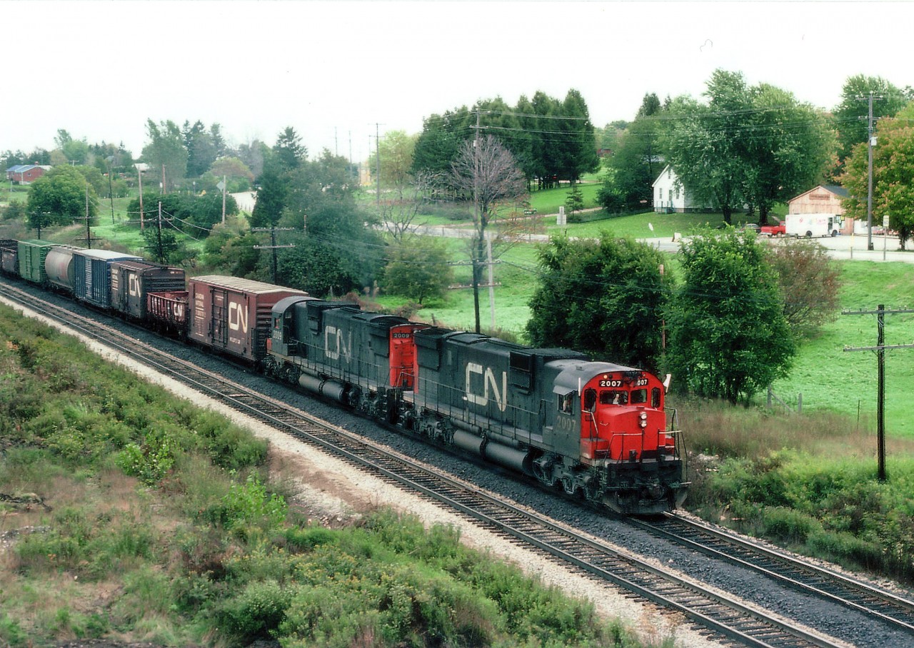 I sure miss the days of the big Alcos. In this scene, a couple of MLW C-630M behemoths ease off somewhat after the long escarpment climb from Bayview Jct. CN 2007, 2009 are on the south track going west. Governor's Rd is in the background.