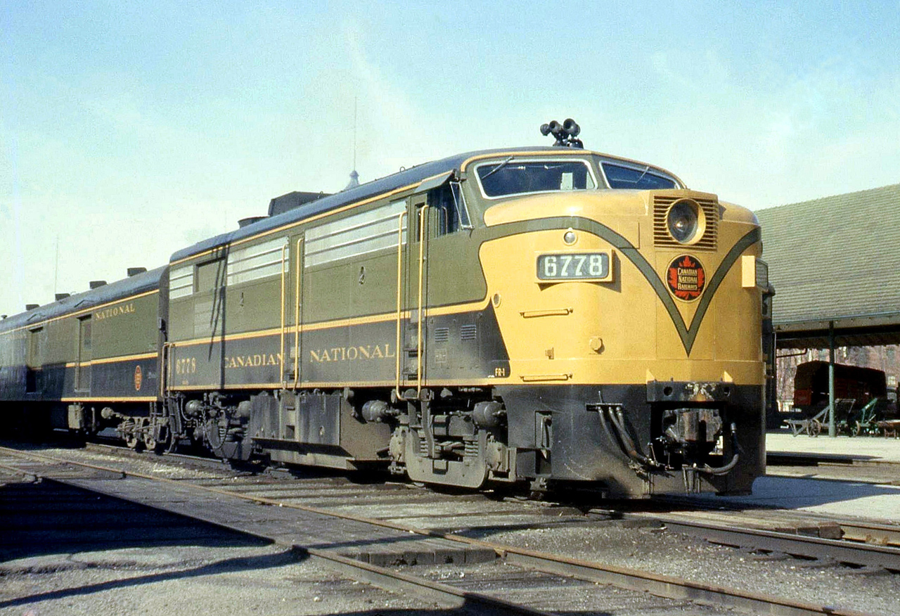 CN train #628 with FPA4 6778 is stopped at Guelph Station in the Summer of 1962, with the lead unit still dressed in the yellow, green and black "1954 scheme" colours. Delivered in 1959, the MLW FPA4 and FPB4 fleet only had 2 years before the CN noodle and zebra stripes were first introduced in 1961. By 1963 only a few FPA4's remained in the 1954 scheme, and by 1965 only one (6765).  [Editor's Addition: According to a timetable from that era, CN train 628 was a daily (except Sunday) morning eastbound passenger train for Toronto via the Brampton Sub (later divided into parts of the Guelph, Halton and Weston Subs), arriving at Union Station in mid-morning.]
