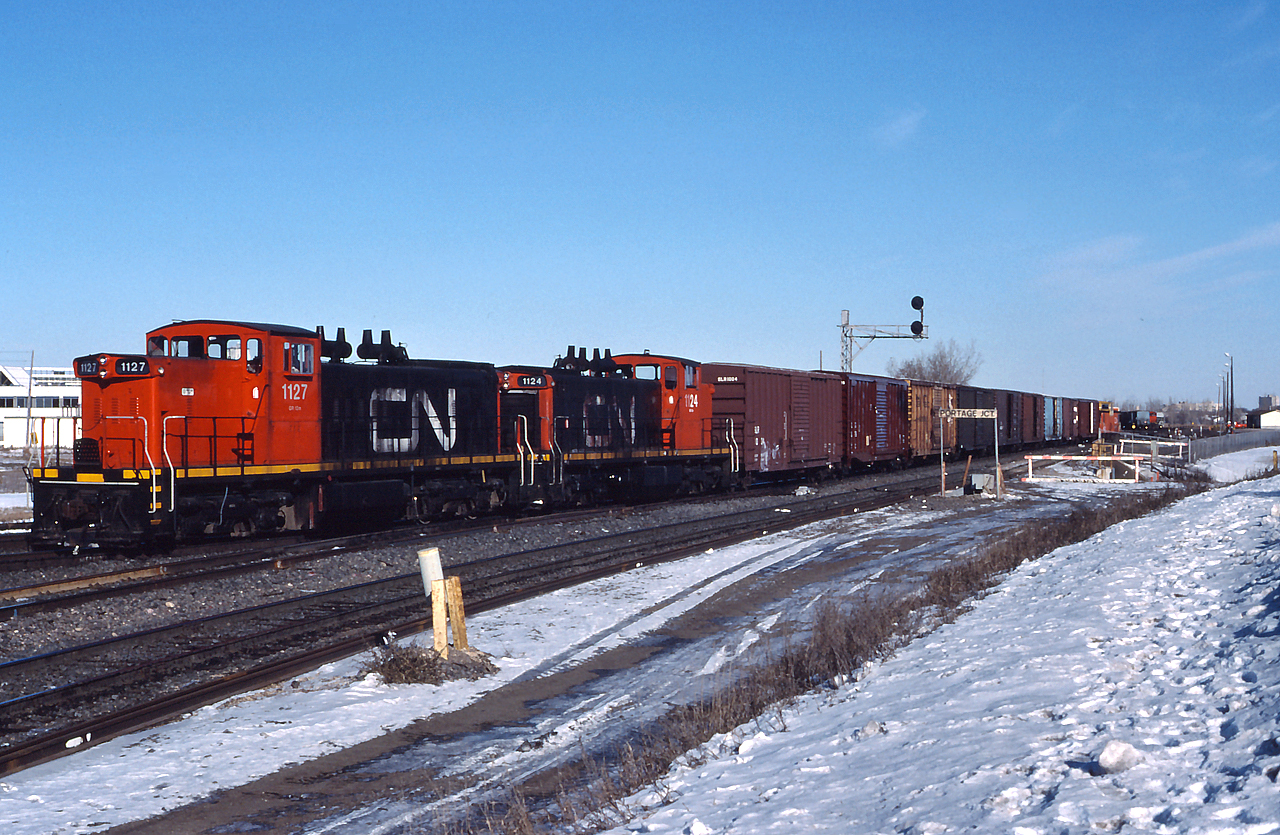 CN 1127 and CN 1124 lead a transfers out of Portage Jct, complete with an International Service caboose.