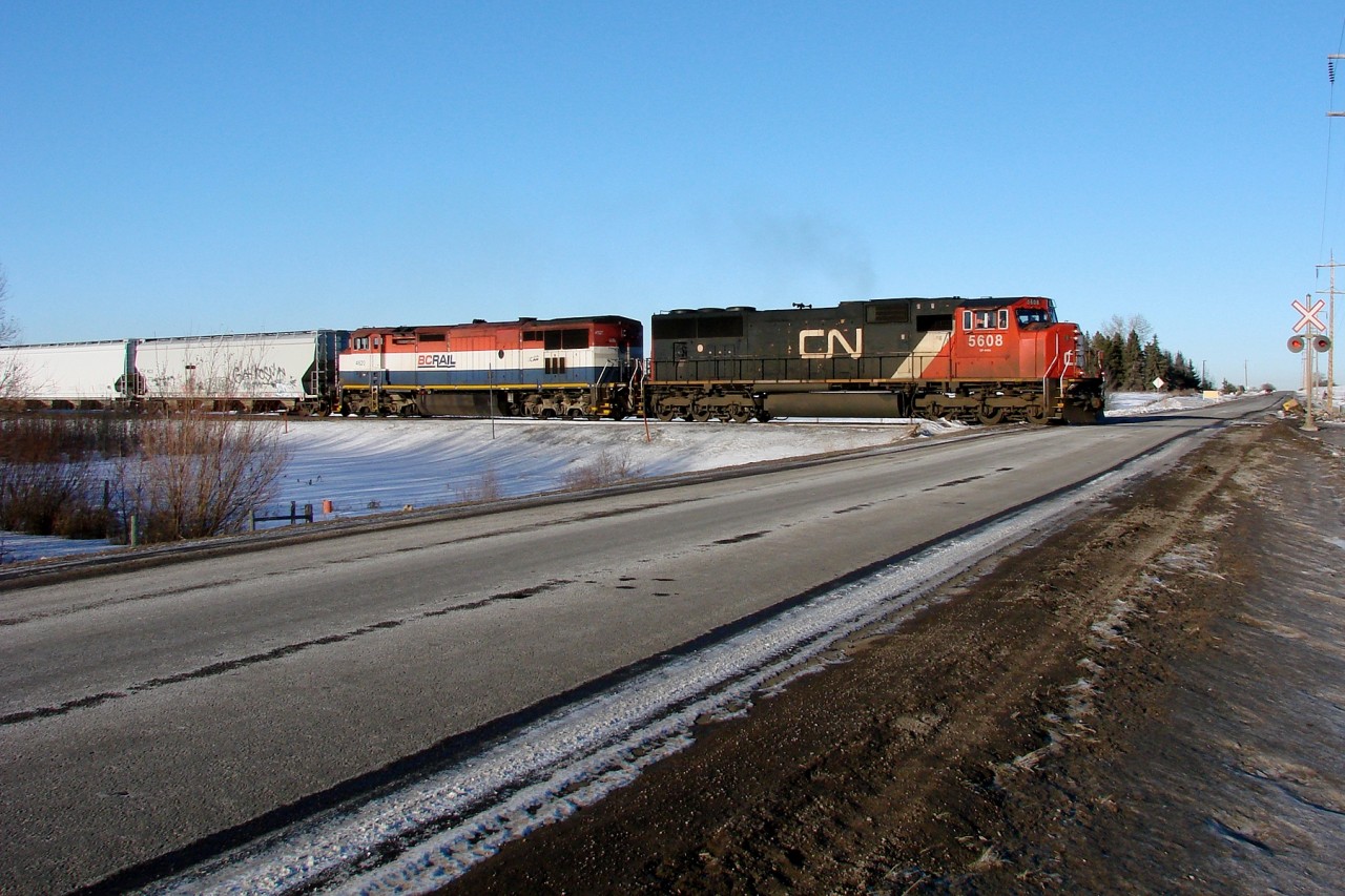 CN 5608 and BCOL 4602 cross Range Road 231 as they travel East on the Wainwright Sub.