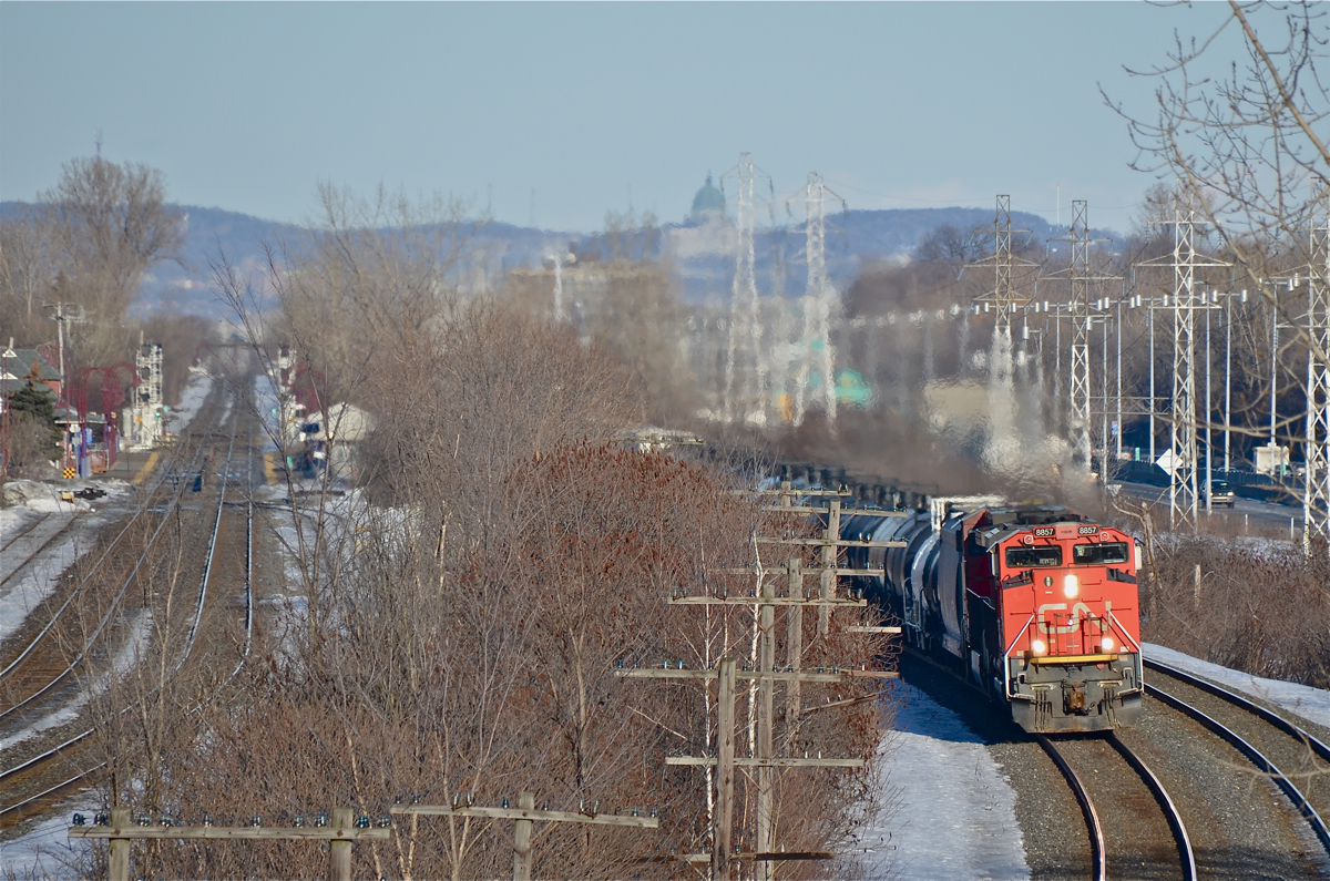 CN 8857 & CP 2681 head west through Beaconsfield with a westbound train, possibly CN 377. At left is the CP Vaudreuil Sub and AMT's Beaconsfield Station. In the distance is Mount Royal, with St. Joseph's Oratory visible in the middle right background. For more train photos, click here.