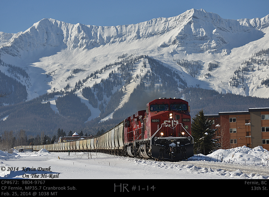 Empty potash 672 with 9804 and 9767 working eastbound on the Cranbrook Sub about to cross the 13th Street road crossing with the Lizard Range and the Fernie Ski resort in the background.