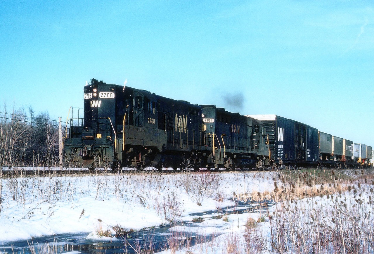 N&W 2708, 2915 head westward approaching Pettit Rd in Fort Erie, exiting yard limits, on its way to St. Thomas. Note old paint style second unit. And it is April, but this looks more like a winter scene. The CSX line is just visible in background ahead of the lead unit.