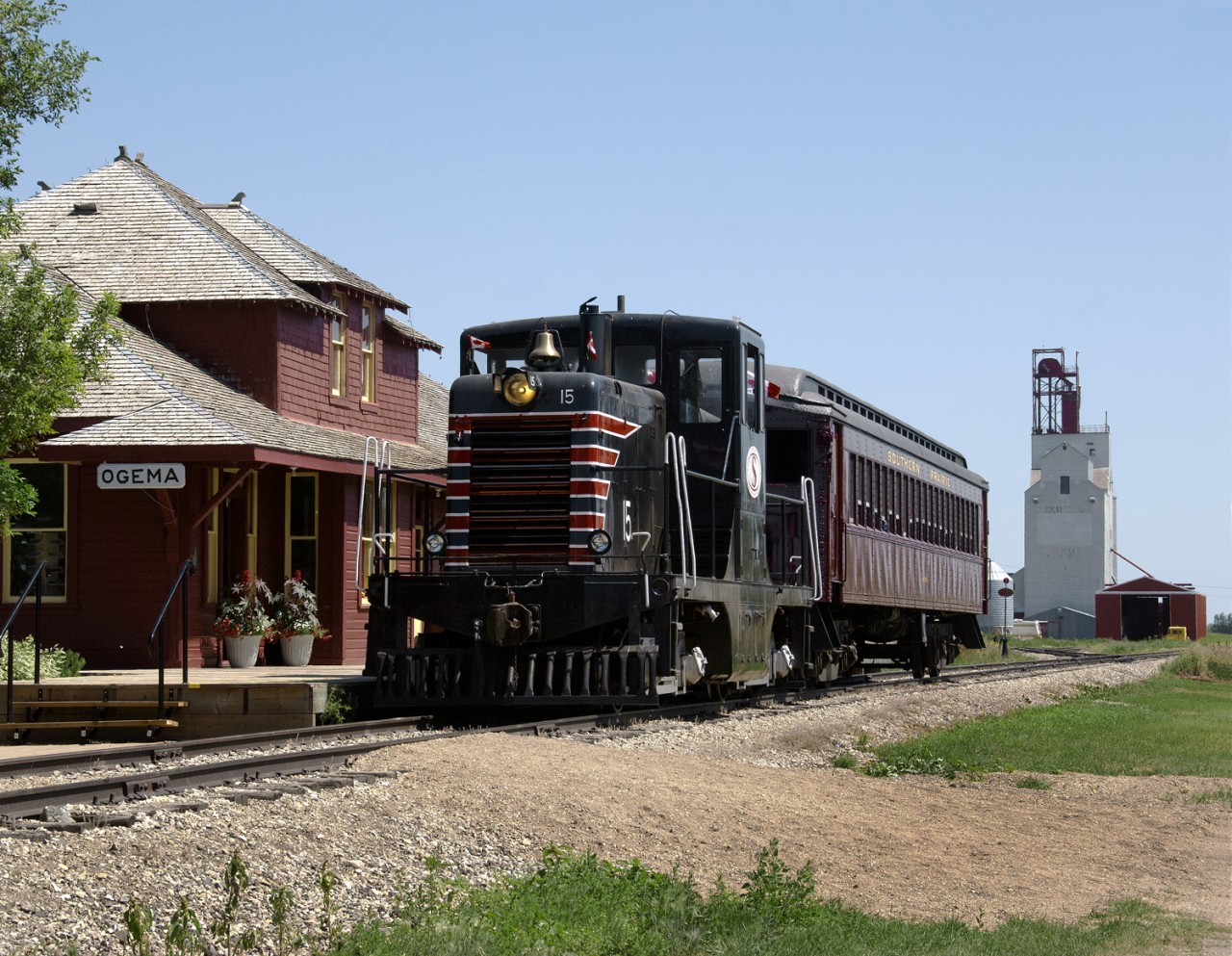 Southern Prairie Railway's ex MEC GE 44t 15 and a former DLW coach Mount Holly gets ready to depart for a return trip west to Horizon Sask on Fife Lake Railways ex CP Assiniboia Sub. The Station was formerly from Simpson Sask. but was of a similiar style as the original Ogema Station..