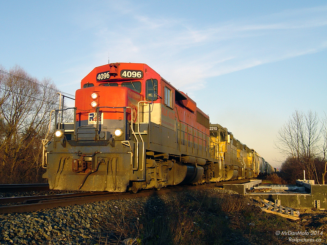 Rolling west into the 4:30pm sunset, RailAmerica GP40 4096 heads up the matching LLPX duo of 2210 and 2236 on Goderich Exeter Railway train 431, crossing over Fletcher's Creek while exercising running rights on Canadian National's busy Halton Subdivision from MacMillan Yard back to the Guelph Sub (at Georgetown). 4096 is back on her old stomping grounds, as she was built in 1966 for CN as 4006 and later renumbered 9306 before being retired and sold.  This segment of track in Brampton was undergoing triple tracking for increased GO Transit train service, which would branch off less than a mile away, just east of the diamond and station downtown. The new bridge span over Fletcher's Creek can be seen installed in the background for the future 3rd track, which would run where the photographer is standing. About 3 cars down is the switch to the Dixie Cup Spur, serving the Georgia-Pacific (former Dixie Cup Company) plant off Queen Street. The switch would be removed for installation of the third track and never reinstalled - the spur would fall into disuse and be ripped up by April 2013.