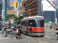 <b>Hustle and bustle of the city streets on a warm summer's day.</b> With pedestrians, cyclists and cars going about their merry way, TTC CLRV 4061 waits to make the turn onto Spadina Avenue from King Street. While some runs of the 510 go to the end of the line at Union Station via Queen's Quay, a number of 510s turn at King and head back up Spadina, to the street's namesake station at Bloor.