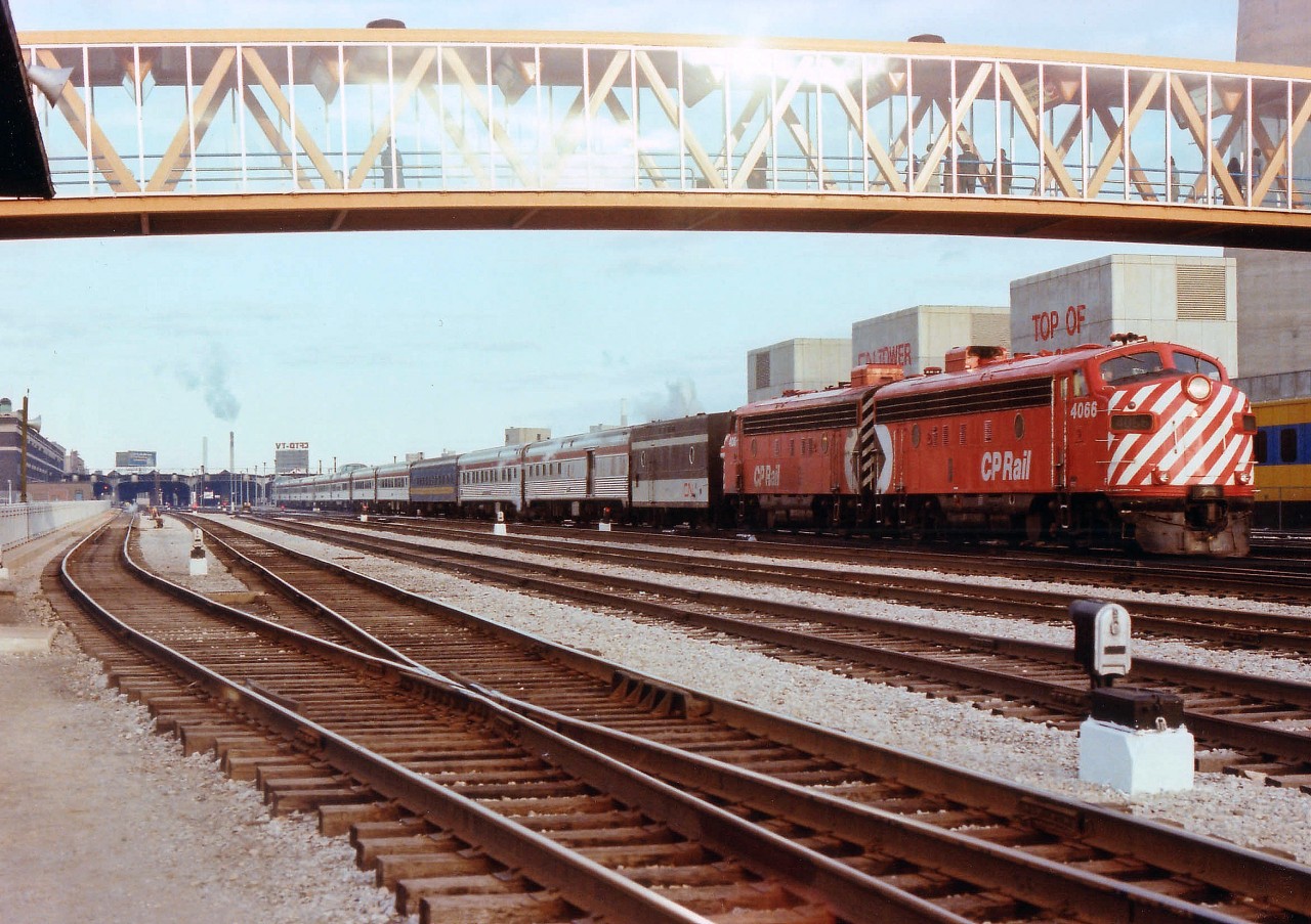 There were a lot of changes when the first new VIA schedule was issued to go into effect October 29, 1978. CN and CP passenger equipment was now shared now that the fledgling VIA RAIL corporation was organized in order to take control of the faltering CN and CP passenger trains. The "Canadian" was now originating/terminating at Toronto on its daily run, destination Vancouver, as trains #1 and #2, while the Super Continental, daily departed Montreal to Vancouver and return as trains #3 and #4. This image, taken from just west of the CN Tower walkway, is of the very first of those "Canadian" passenger trains that have become so popular over the years. Power up front is CP 4066 and 4067, with a CN steam jenny and a CN coach partway back, in an otherwise solid CP consist. Departure point Union Station can be seen in the background. A few pedestrians, possibly uninformed as to the historical significance they are witnessing, watch from overhead.