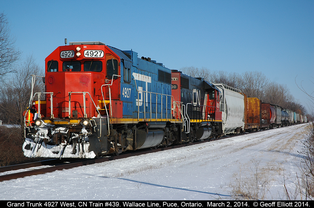 The Brakeman rides the steps of rare blue Grand Trunk GP38-2 #4927 as is approaches Wallace Line in Puce, Ontario today.  Slow orders for crossings and bridges keep the train moving relatively slow on the Windsor end of the Chatham sub, but the slow orders only apply to the freight traffic and not the regular VIA trains.