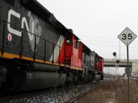 The top eastbound signal is lit up amber for the descent into Brampton, but CN 338 is going nowhere fast - 10,300 horsepower idles away on the outskirts of the city on a cold winter's day, awaiting the arrival of a new crew. The old SD40-2 nearest the photographer proudly displays the "CN North America" logo, something that didn't last too long before being dropped from new deliveries and repaints. Trackspeed from this point east slows to 35mph into town, for crossing the interlocking diamonds of the OBRY's Owen Sound Spur.
<br><br>
The new Chinguacousy Road bridge was opened not too long ago, and the old roadway crossing was still in place here, albeit blocked off, serving as an access road for crew change vehicles. Once the new crew is taxied and and set up on their train, 338 would be on the move again to cover the final 17 miles to its termination point at MacMillan Yard in Concord.