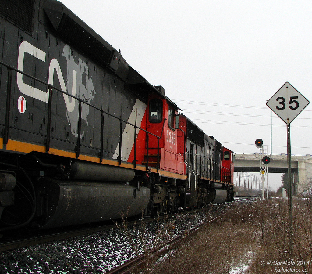 The top eastbound signal is lit up amber for the descent into Brampton, but CN 338 is going nowhere fast - 10,300 horsepower idles away on the outskirts of the city on a cold winter's day, awaiting the arrival of a new crew. The old SD40-2 nearest the photographer proudly displays the "CN North America" logo, something that didn't last too long before being dropped from new deliveries and repaints. Trackspeed from this point east slows to 35mph into town, for crossing the interlocking diamonds of the OBRY's Owen Sound Spur.

The new Chinguacousy Road bridge was opened not too long ago, and the old roadway crossing was still in place here, albeit blocked off, serving as an access road for crew change vehicles. Once the new crew is taxied and and set up on their train, 338 would be on the move again to cover the final 17 miles to its termination point at MacMillan Yard in Concord.