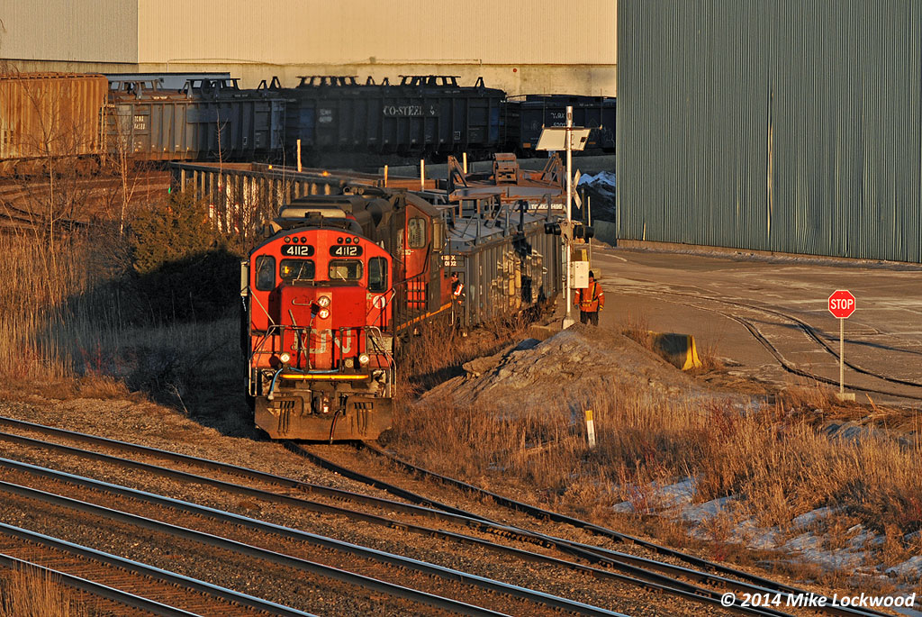 In the dying light of a perfectly sunny and cold winters day, CN 4112 and 7029 pull four loads from the Gerdau Ameristeel plant in Whitby, Ontario. Arriving light from the yard in Oshawa and after a brief fight with the switch into the plant trackage off the South Service track, they darted into the plant yard, grabbed their lift, and retreated back to Oshawa. 1856hrs.

Wonder when this type of scene will be a thing of the past? With 50 plus years under their belts, he GP9 has surely outlived the iron horses that they replaced in the 1950's... a remarkable feat given the mileage they've racked up before and after remanufacture, and the fleets that have come and gone while they've kept toiling away with little fanfare.

CN 4112 started life as CN 4249 in 1958, so she isn't one of the oldest on the roster, however having been remanufactured into a GP9RM in 1984, she has actually toiled in this form longer than in her original high hooded configuration.

The trailing unit, CN 7029, was built as CN 4150 in 1959, renumbered to 4391 in 1984 to make room for the 4100 series GP9RM's (which never went above 4143). CN 4391 Finally went into PSC for conversion to a yard goat in 1991.