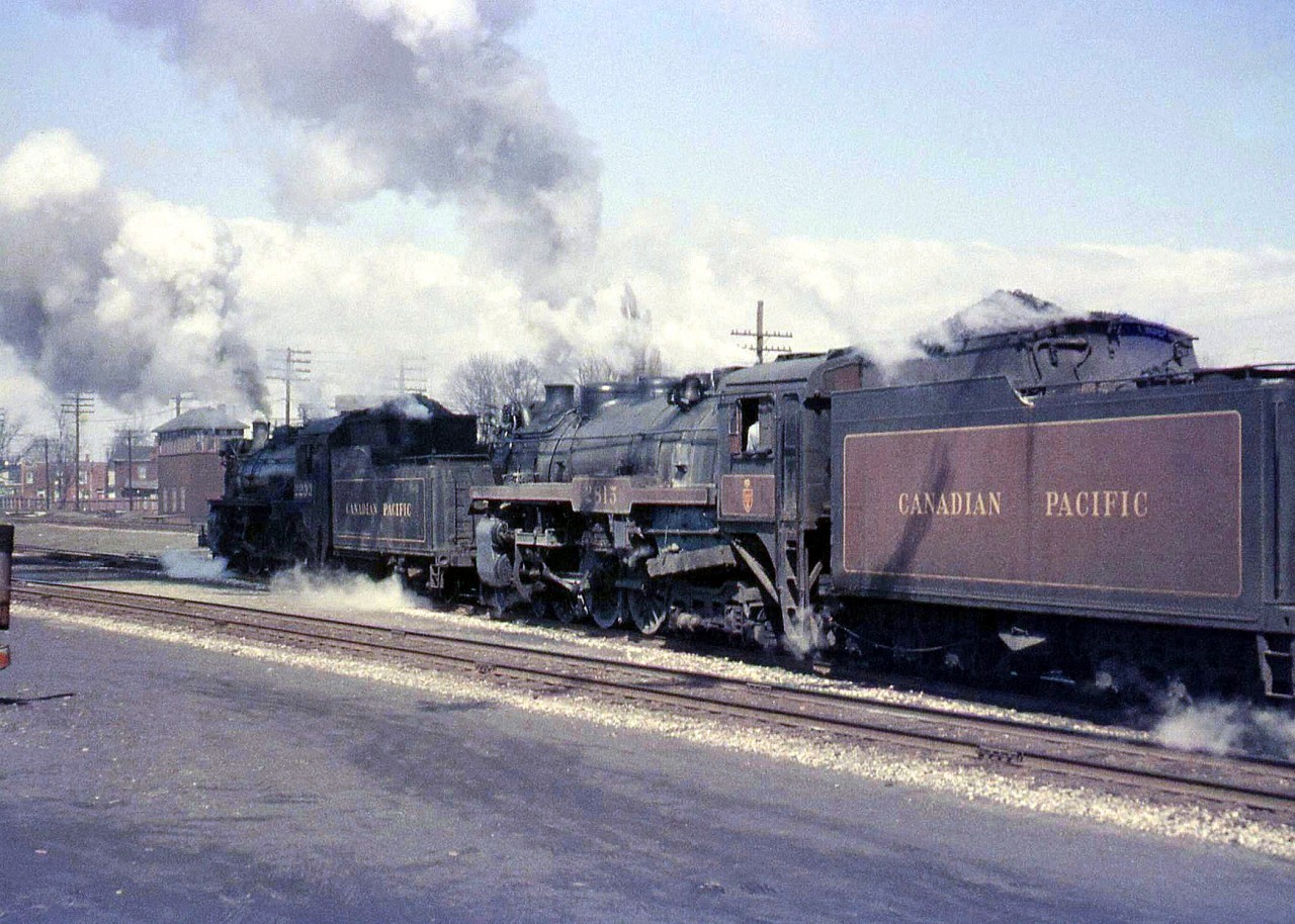 Steam Doubleheader! CPR G1-class Pacific 2232 assists H1b-class standard Hudson 2815 as they pass by West Toronto Station in a cloud of smoke, about to cross over the diamond(s) at West Toronto junction and head north on the Mactier Sub. Note the West Toronto interlocking tower, demolished sometime in the mid-late 60's when the interlocking plant was modernized. The train is about to take the connecting track leading from the east track of the Galt Sub, across the double main tracks of the North Toronto Sub, and onto to the MacTier Sub (the ex-Toronto Grey and Bruce line) just to the north. Often used by The Canadian in later years, it's since been removed. West Toronto Station was demolished by the CPR in 1982, despite efforts by groups and the city to save it.