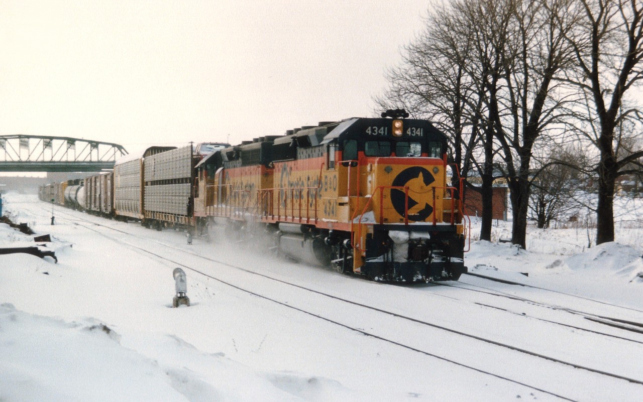 Snowy and blustery winter afternoon at Fort Erie as B&O 4341 and 4115 haul the daily transfer from F.E. yard over to Buffalo. Central Av bridge in background and the relatively new flat roofed Michigan Central station can just be seen at the right of the lead unit. Station is history. It ran out of usefulness when the CP/TH&B Budds ceased operation thru here in 1981.