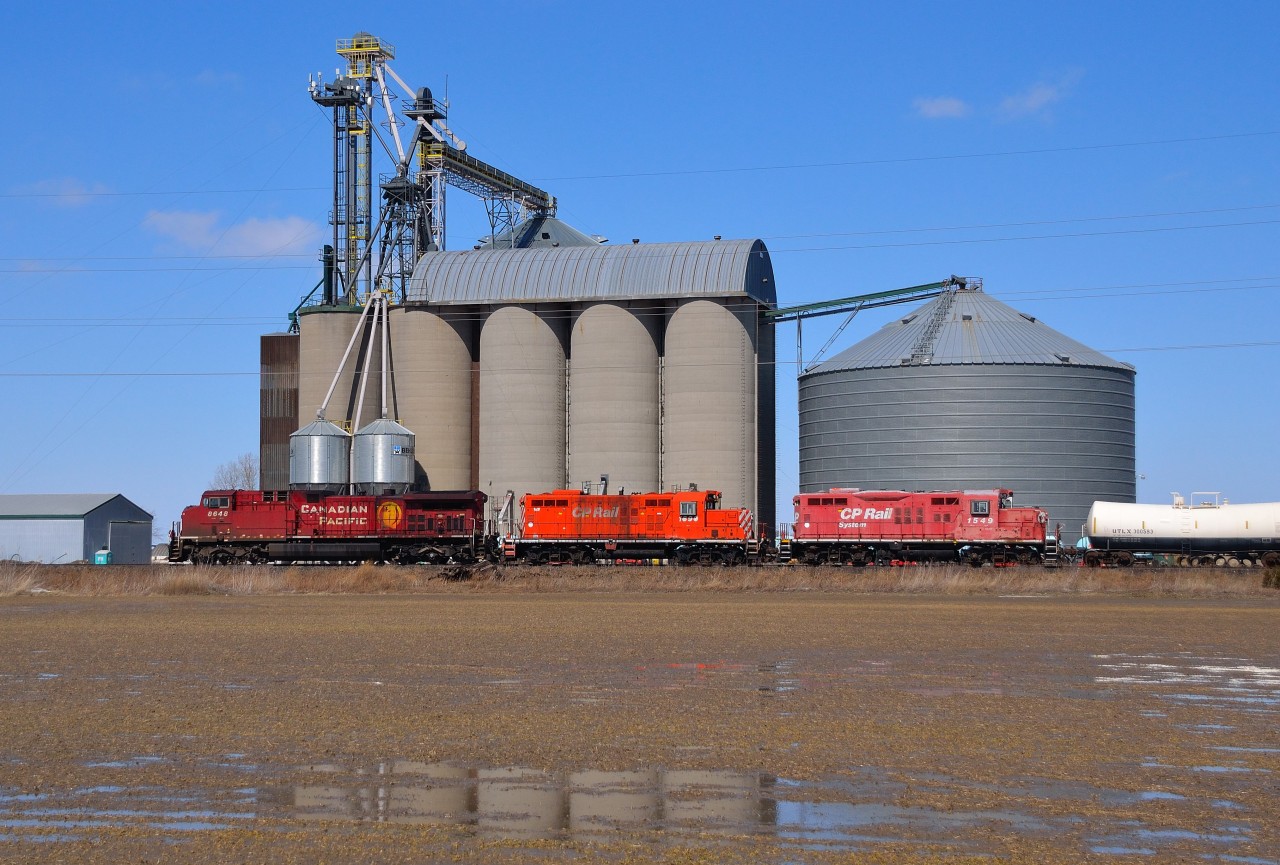 CP 8648 with GP9's 1690 & 1549 in tow, heads westbound past the grain elevator at Haycroft. The Geeps are probably headed for the scrapper.