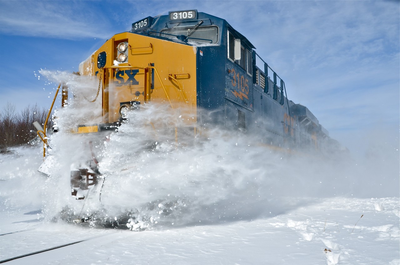 CSXT 3105, one of CSX's newer ES44AH's with the new boxcar logo leads CN 327 southwards, with CSXT 867 trailing. It is smashing through the snow piled up at a rural crossing the day after a snowstorm. In a few miles at Huntingdon the train will be left with an American crew and the Canadian crew will take CN 326 northwards. For more train photos, click here.