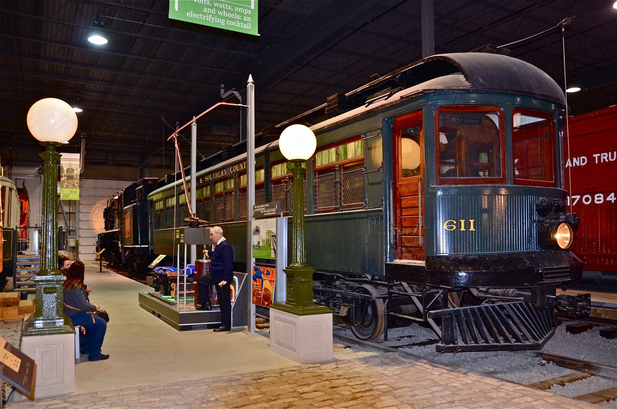 Teaching about trolleys. An Exporail volunteer demonstrates how a trolley operates, with a preserved example behind him. MSC 611 was built by Ottawa Car in 1917 for the Montreal & Southern Counties, an interurban which operated between Montreal and Granby on the south shore of the St-Lawrence river. For more train photos, click here.