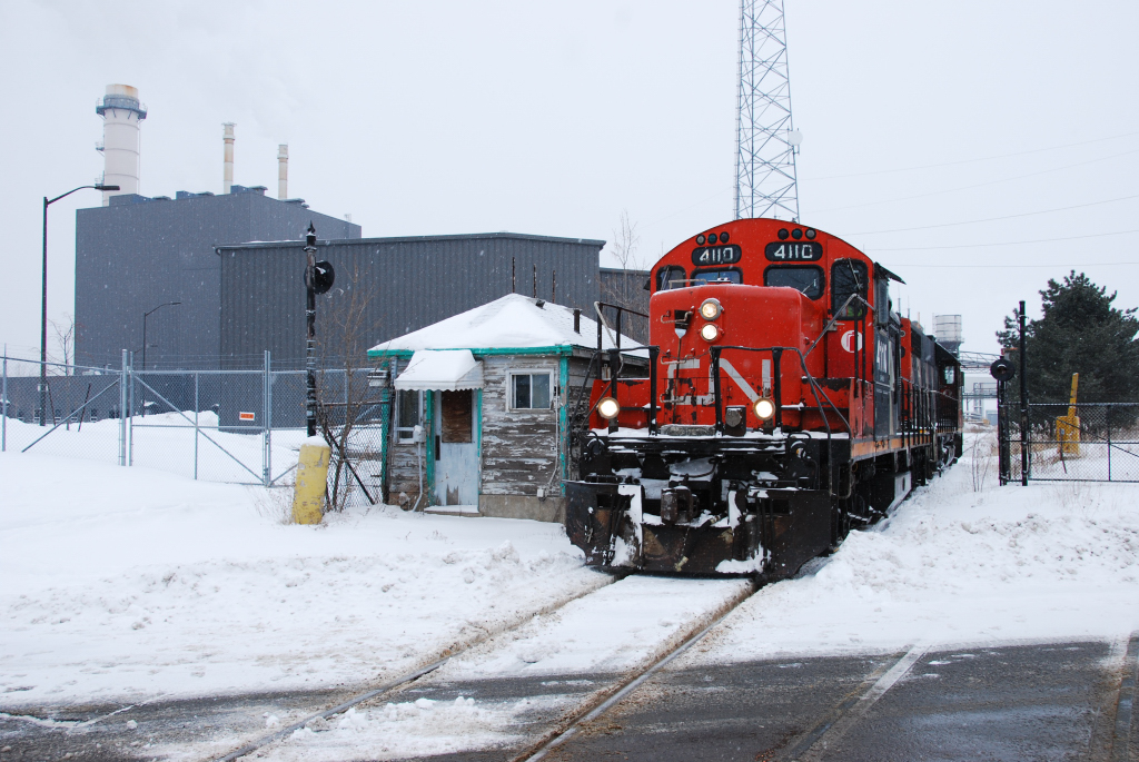 CN L562, the dayshift Port Robinson switcher, is leaving Resolute Paper in Thorold, passing a long-disused gate house.  Usually this trackage is operated by the mill locomotives, but they must be down for the count today.