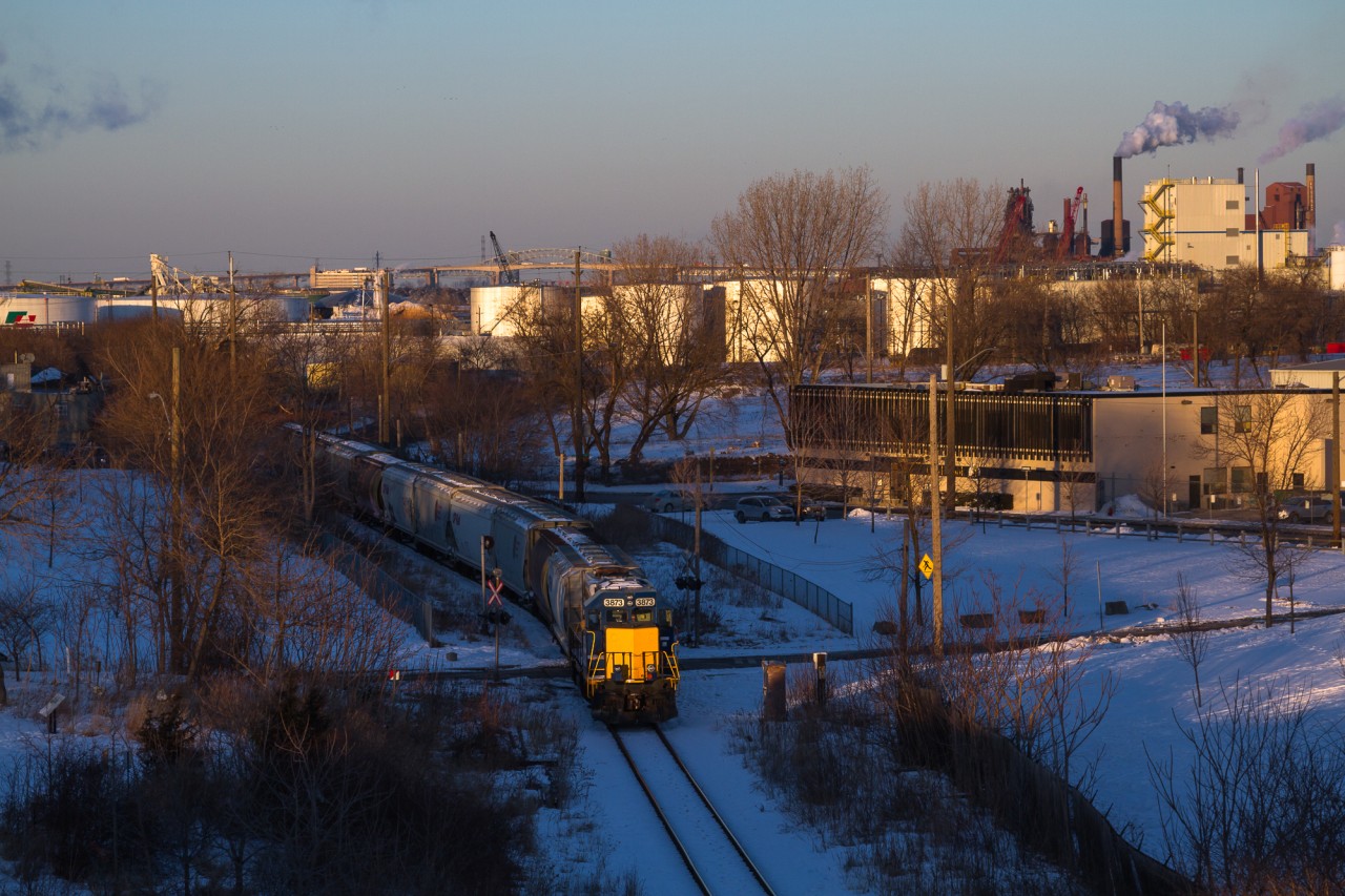 Another cold winter's day is coming to a close as RLK 3873 shoves a healthy string of grain cars towards Bunge Inc., along the old N&NW Spur. Some of Hamilton's many waterfront industries and the Skyway bridge, can be seen in the background.