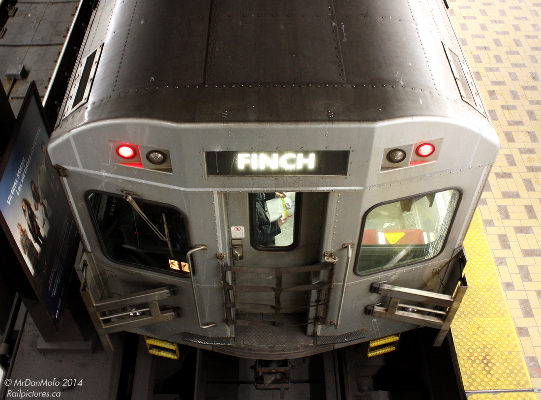 Sitting, talking, standing, and (in this case) reading, a train full of passengers stops briefly at the busy St. Clair West Subway Station before departing northbound. The train will switch ends at the end of the line a few stops up, and the trailing TTC T1 subway car pictured will lead the trip south, back through St.CW again on its way downtown.