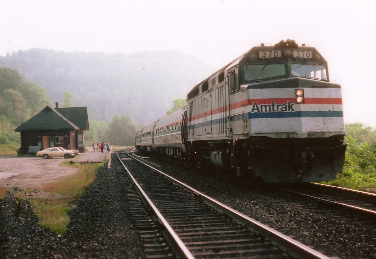 The Amtrak International Limited has stopped on signal at Dundas in order to pick up passenger(s) on its 0915 arrival time on a rather foggy September morn. On clear days, sun angle would make this photo almost impossible. Others out front of the station are awaiting the VIA Tempo #71, close behind.