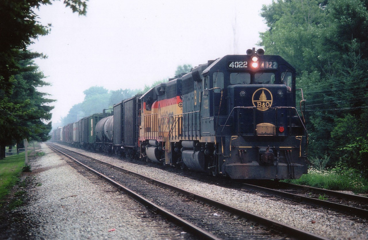 Back when the mainline that ran from the Niagara bridge down to Brookfield was double tracked thru the city of Niagara Falls, we see the late (steamy) day #321 with an old paint leading, B&O 4022, with the newer Chessie System yellow 4394 behind. The train is around Milepost 1 which paralleled Palmer Av in town. Hard to believe this image was taken in the city.
