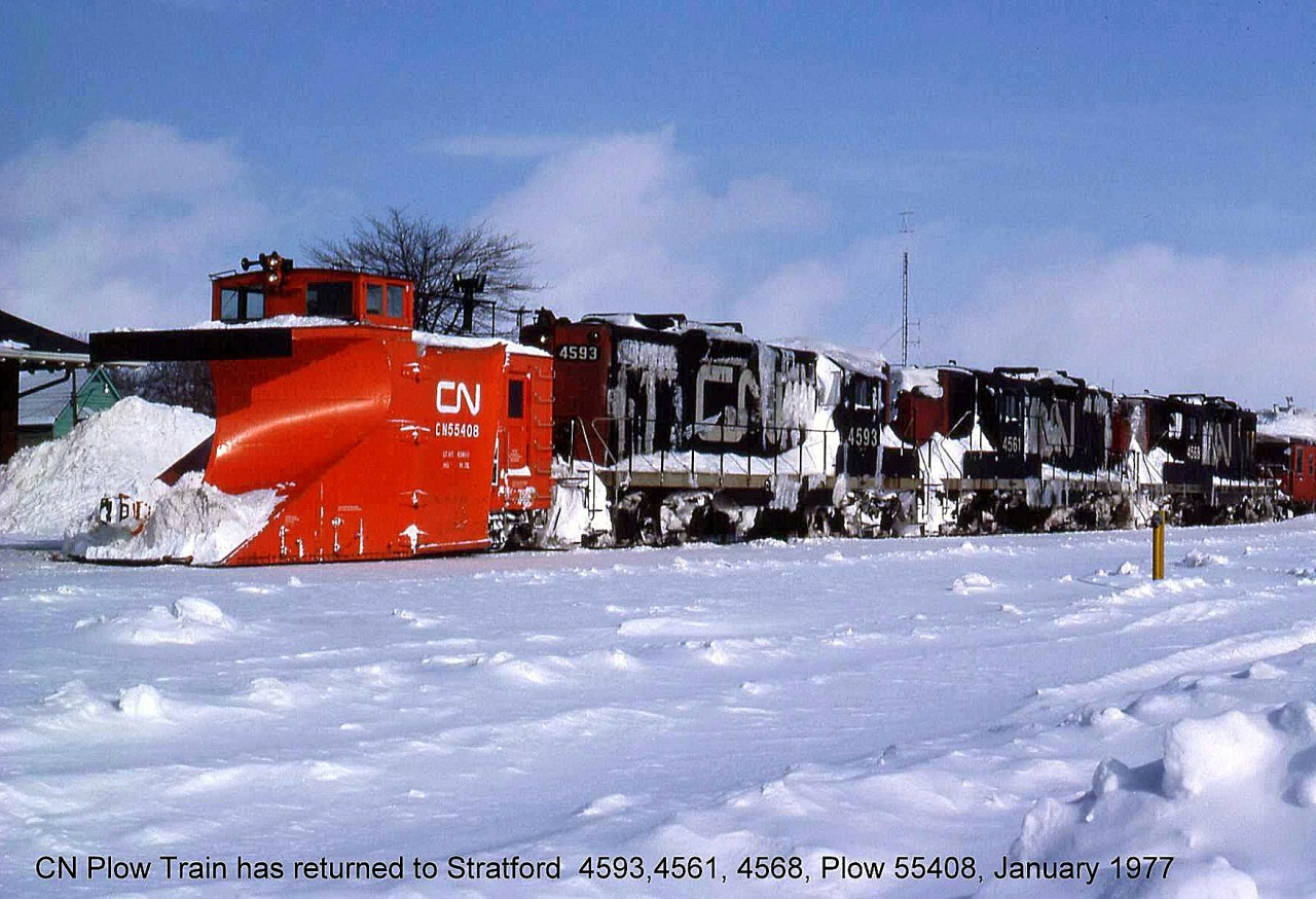 After a day of plowing in Ontario snowbelt country, a CN plow train rests back in front of the station at Stratford. CN plow 55408 has plenty of power behind it, pushed by a trio of frozen looking GP9's (4593, 4561 and 4568). A snow-covered van punctuates the rear of the train, although if the crew inside of it could see anything going on ahead of them is anyone's guess.  For another view of CN 55408 (that later went GEXR) plowing on the "Bruce branches": http://www.railpictures.ca/?attachment_id=13997.  And a CP plow train: http://www.railpictures.ca/?attachment_id=14417.