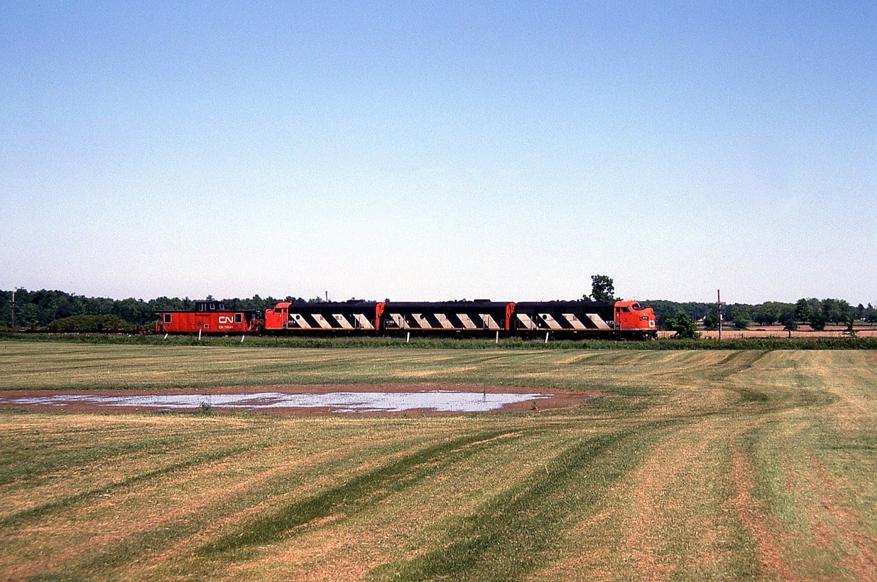 To follow up on Arnold's great Ferguson Avenue photo of the CN Steel Train, here's a photo of it running along the Hagersville Sub near Rymal on the Niagara escarpment, with a nice matching zebra-striped A-B-A set lead by CN 9173.

[Editor's notes: CN for a time ran the Steel Train out of Hamilton with matching A-B-A sets of F7 units. While they were poor for switching, crews reportedly didn't mind as there was little switching done with the train. Occasionally a GP9 would be substituted for an ailing F.]

Note: Geotagged location not exact.