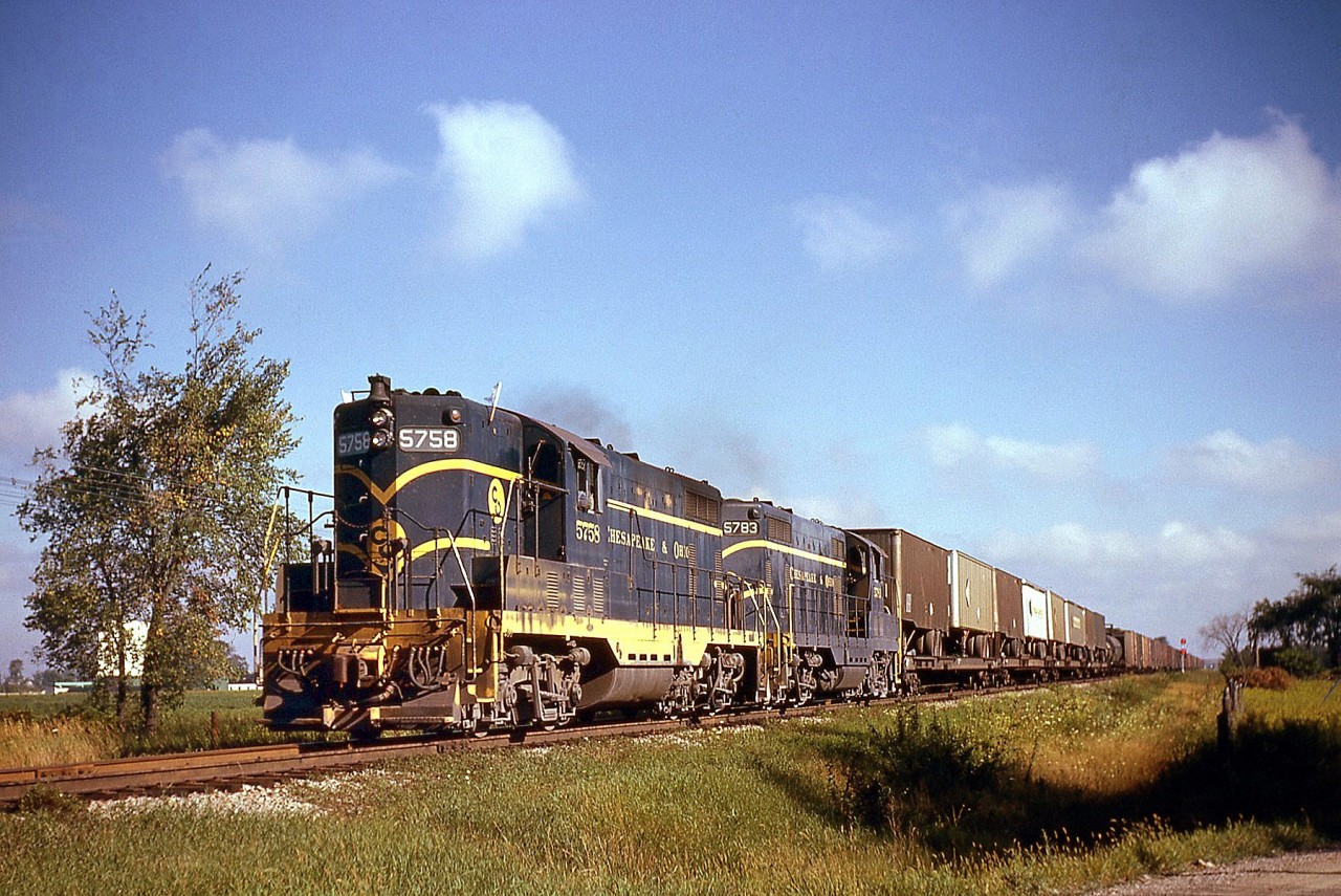With white flags flapping on their high short hoods, Chesapeake & Ohio GP7's 5758 and 5783 roll eastbound near Oldcastle ON on C&O's Subdivision 1 with TOFC piggyback loads (Trailer On Flat Car) up front and general manifest at the rear. Running from Walkerville to St. Thomas, the line later became the CSX Blenhein Sub, and today aside from a small spur at Blenheim the line is abandoned.Note, Geotagged location not exact.