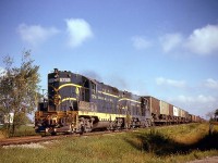 With white flags flapping on their high short hoods, Chesapeake & Ohio GP7's 5758 and 5783 roll eastbound near Oldcastle ON on C&O's Subdivision 1 with TOFC piggyback loads (Trailer On Flat Car) up front and general manifest at the rear. Running from Walkerville to St. Thomas, the line later became the CSX Blenhein Sub, and today aside from a small spur at Blenheim the line is abandoned.<br><br><i>Note, Geotagged location not exact.</i>