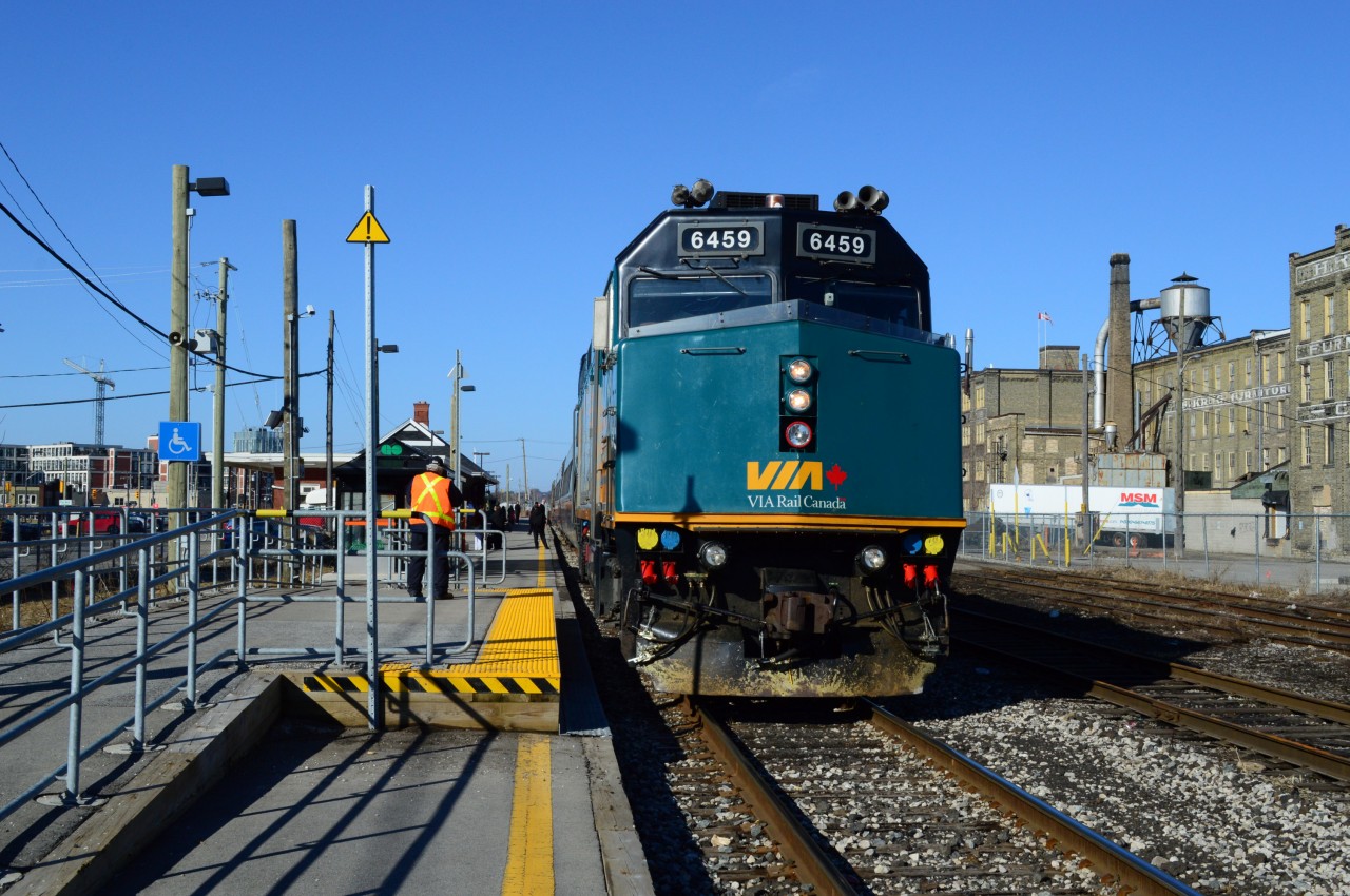 Twenty five minutes off the timetable Via 84's  ( powered by 6459 (nee 6403))  head end crew enjoys the convenience of GO Transit's accessibility platform at Kitchener.


Underpass construction (Weber Ave?)  west of the Kitchener station forces passengers to entrain / detrain at the east end of the new Go platform.


What's interesting: 


see 6459's re-builder's plate: 


  6459 re-builder plate   


Eight years ago 6403 formerly sported the CBC 50th Anniversary scheme:


  CBC paint   


April 6, 2014, image by sdfourty.