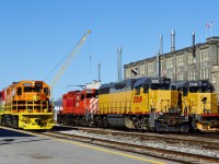 On an April Sunday morning ten minutes after 84 departed,
<br>
<br>
see:
<br>
<a href="http://www.railpictures.ca/?attachment_id=14582">  train 84  </a> 
<br>
<br>
 the GEXR rolls into Kitchener.
<br>
<br>
The six GEXR units are an interesting mix:
<br>
<br>
from the left and the (barely visible ) trailing unit #3821 (plain GP 38 EMD 11/1967, ex Salt Lake Southern) in red, grey with white stripes;
<br>
<br>
Middle unit RLK #4095 (GP 40 EMD 6/1966) in red, silver and blue;
<br>
<br>
Lead unit GEXR 2303
<br>
<br>
and in the overnight storage tracks: 
<br>
<br>
ex CP GP 9u  8235 (nee CP 8822 GMD GP9 1958 )
<br>
<br>
LLPX 2210 (GP 38AC EMD 11/1971, nee GTW 5806)
<br>
<br>
LLPX 2236 ( GP 38-2 EMD 2/1976, nee LIRR 262)
<br>
<br>
The crane in the background is part of the new (Weber Ave) underpass construction.
<br>
<br>
April 6, 2014 image by S. Danko.
