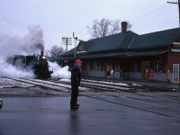 Former CP 4-4-0 136 gets flagged across George Street on a dreary warm March day. 136 and a train of two cars with people in period clothing were being filmed by a CHCH tv crew for a Christmas special by the Dofasco choir.