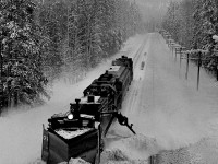 Heading for the snows on Rogers Pass a westbound plow extra based at Golden rolls past Donald with the spreader winging snow clear of the passing track. Mount Moberly looms over the scene.