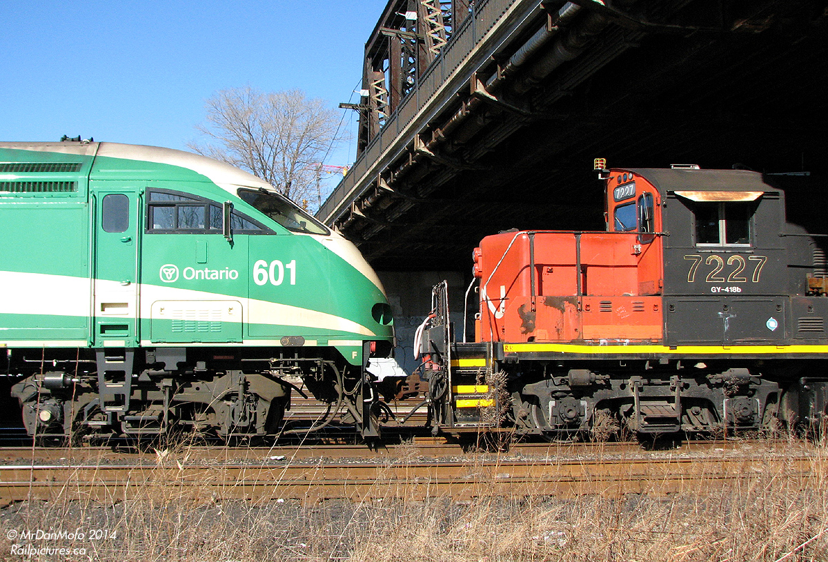 Young Beauty and an Old Beast.  By some odd coincidence, this happened: a brand new GO MP40 (perhaps being picked up from Mimico for some warranty work in Welland?) coupled backwards on the head end of a work extra powered by a CN GP9RM and slug, with a ton of ballast hoppers and boxcars behind, sitting in the Union Station Rail Corridor in the afternoon.  I'm not sure what they were doing there, or why GO 601 was leading rear-end-first, but seeing it from the Gardiner Expressway was enough for me to walk from Union Station to Bathurst Street to get some photos. The train wasn't positioned well for shots from the bridge above, but the Fort York area to the west was open and working around the high chain-link fence, a few shots were had of this odd lashup.  The streamlined MPI MP40PH-3C was built in Boise ID for GO Transit commuter service a few years ago. The utilitarian GM GP9RM, 7227, was built as CN 4563 in the 50's and was likely pressed into passenger service with steam generator cars a few times before being rebuilt for yard service in the 80's. The torch has been passed, but the 7227 will probably get the last laugh: I can't see MP40's surviving in 50 years downgraded to freight service.