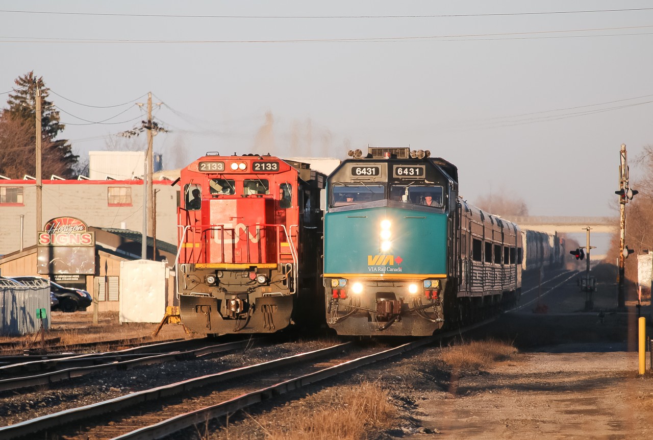 As Via 75 slows down on the approach to the Woodstock Via station, CN M399 slides by on the north track.