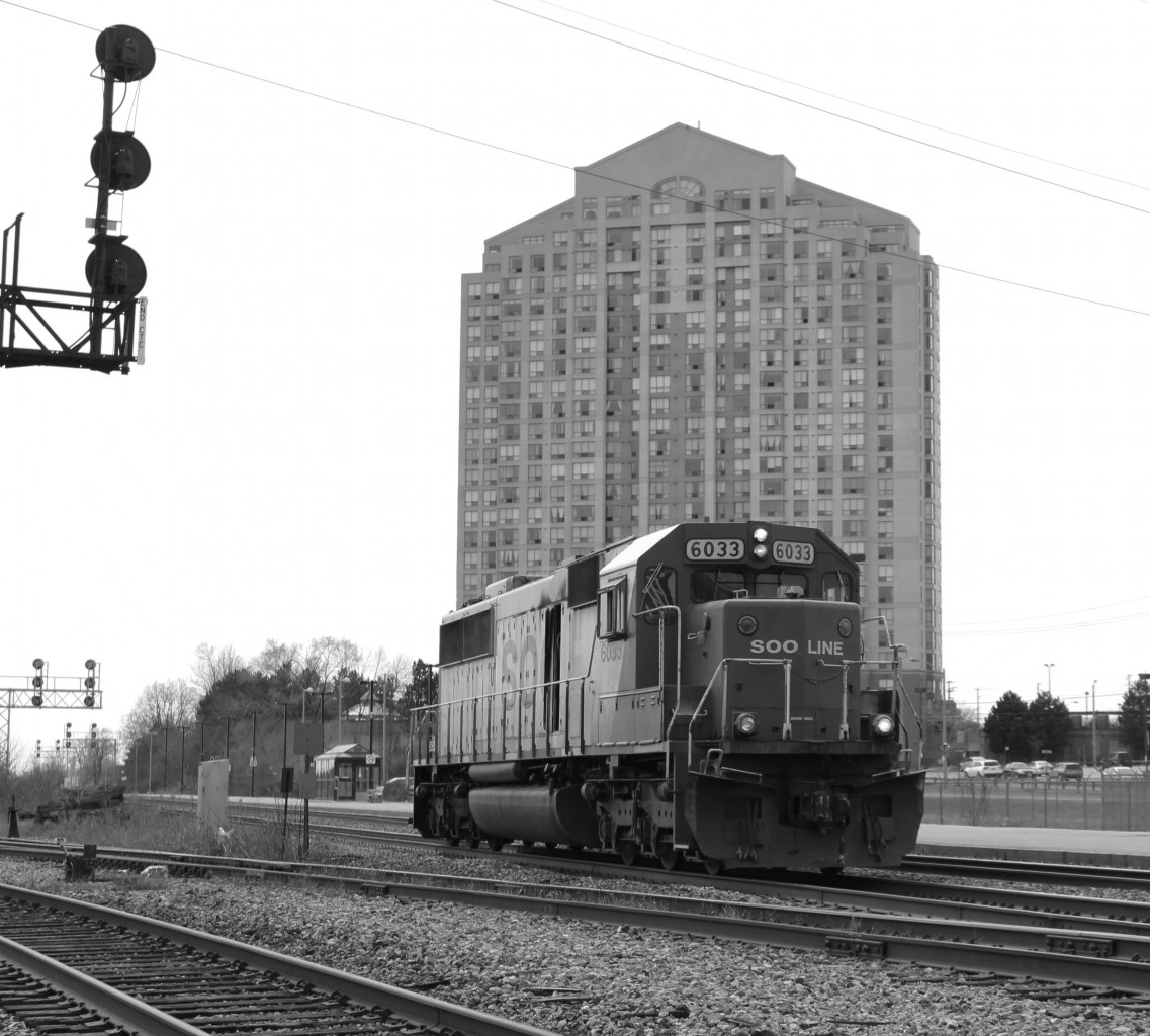 This overcast lighting very appropriately sets the mood for this shot of SOO 6033 as it passes Kipling GO Station. With fire damage to the right side, and a non-working ditchlight, this SD60 is bruised, battered and tired. This may very well be its last run ever. Chances are it will be rebuilt hosting CP colors, or if unlucky it'll be scrapped. Whatever its fate, this SOO will soon be no more.