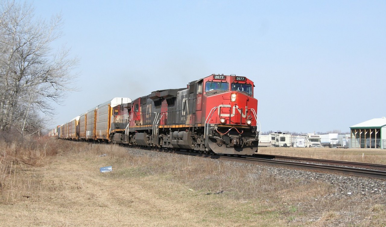 CN 149 breaks the quiet calm of a beautiful spring morning in the village of Kerwood, ON on CN's Strathroy Subdivision.

This train has got to be the first intermodal train that I've ever given chase to. I had just headed to the tracks at one of my favourite locations at Waterworks Road in Sarnia, when I heard 149 on the radio. The conversation indicated that they were having issues with their power, with only one of the three units operational, and that they were making about 15 MPH (indeed, I heard the hot-box-detector give a readout of 16 MPH when they crossed it). With no indication of other traffic at that time, and given their slow rate of progress and that I was ultimately headed to the Waterloo area later that day for an operating session at my model railway club, I decided to head east to catch this train, figuring it would be an easy catch on the other side of Wyoming. And so the chase was on...

Well, I finally caught up with it on the far side of Watford, and it was not doing 16 MPH...

I got in front of it and stopped at Kerwood for this photo. The next detector they hit indicated a speed of 50+ MPH. I guess they got their issues sorted out...

Fortunately I was at least rewarded in the chase with a BCOL trailing unit.

At School Road siding, they overtook CN 509, which I caught in Strathroy.