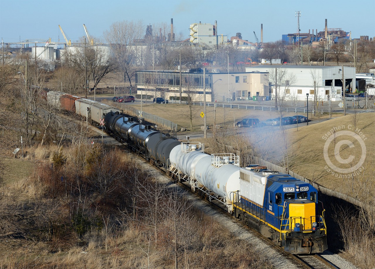 Ferguson ave still creates railway memories, but not as profound as  Arnold Mooneys shot, presently our #1 image alltime. With industrial Hamilton in the background, SOR 495 is headed back to the yard on the N&NW Spur and chugging mightily up the grade, about to pass under Ferguson Ave to meet the CNR Grimsby Subdivision. RLK 3873 sports a rather tasteful patch job, eliminating the Raillink logos, most likely a transitional scheme before application of G&W Orange.
For the history buffs - the N&NW Spur, (Formerly the Hamilton & North Western railway mainline) had a grade seperated underpass with the Great Western at this point (which survived well into the CN Days) and a roundhouse, shops and yard existed just to the south (Behind me) - the outline of which can still be seen today, but has only in the last 2 years been re-developed. The famous Ferguson Street running would be just south of me - itself part of the former H&NW mainline. The N&NW Spur runs into the industrial spurs in the background, and used to cross the QEW/HWY 2, north across the beach strip, meeting the Oakville sub at Burlington West. The Halton sub to Georgetown is also part of the former H&NW Railway, as is the SSR at Tottenham, and the SOR Hagersville sub from Caledonia to Garnet.