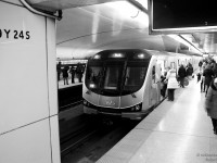 While passengers walk to the exit near the Eatons Centre, others get aboard a new Toronto Rocket subway train at busy Queen Station in the downtown core, along the Yonge-University-Spadina (YUS) line.
<br><br>
The 6-car Toronto Rocket trains were purchased in part to expand the capacity of the overcrowded Yonge Line, featuring about 10% extra capacity per trainset. They were deployed and are exclusively used on the YUS, while other subway trains move to the Bloor-Danforth line to retire the older Hawker cars, including the <b><a href=http://www.railpictures.ca/?attachment_id=14619>H4</a></b>, <b><a href=http://www.railpictures.ca/?attachment_id=10050>H5</a></b>, and <b><a href=http://www.railpictures.ca/?attachment_id=12172>H6</a></b> models.
<br><br>
Small sections of the original 1950's Vitrolite glass tiling remain in very few places on the system, like here on the left, along the north end stairwell walls at Queen Station. Virtually every other original Yonge line has had their tiles replaced over time with ceramic or other materials, with the exception of Eglinton.
<br><br>
The station codes like this one on the Vitrolite denote stairways, escalators and other access points at each station. Queen is the 9th Station on the Yonge-University line (starting from St. George and counting around the loop) and this is Staircase 24 (or something along those lines).